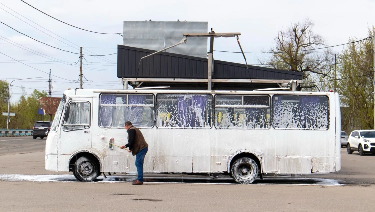 A team member washing a white bus in a parking lot