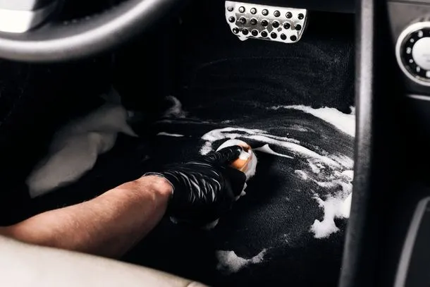 A person cleaning the interior of a car with a sponge
