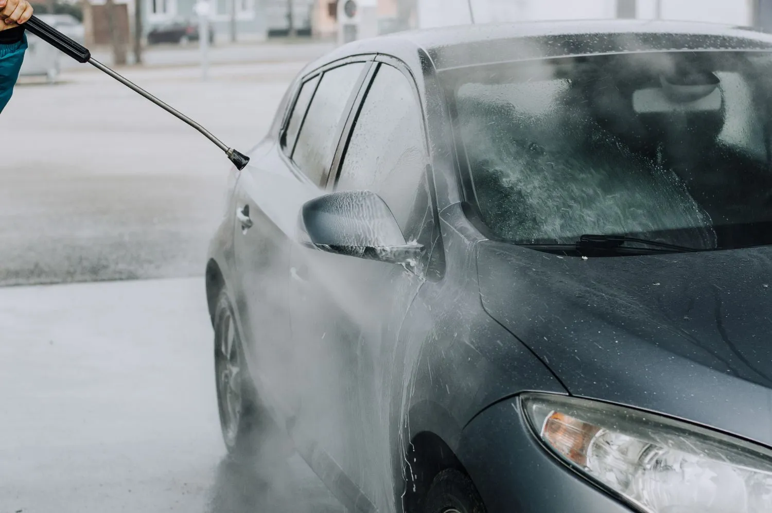 A person washing a car with a high pressure washer
