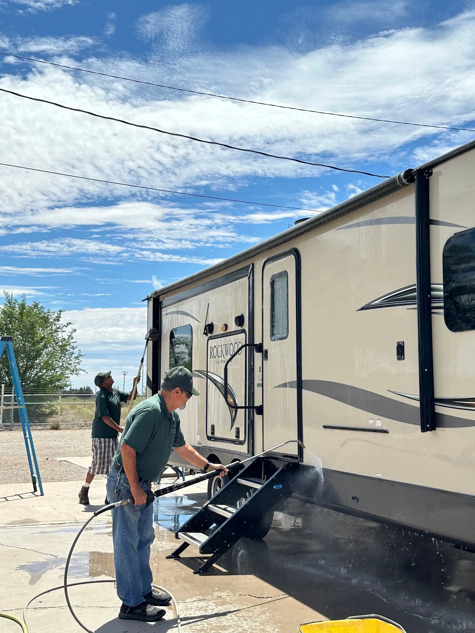A team member washing a large RV at an RV park